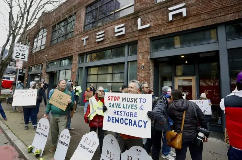 Protesters outside Tesla showroom with anti-Musk signs